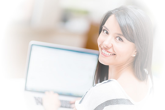 Smiling woman looks over her shoulder, away from computer screen